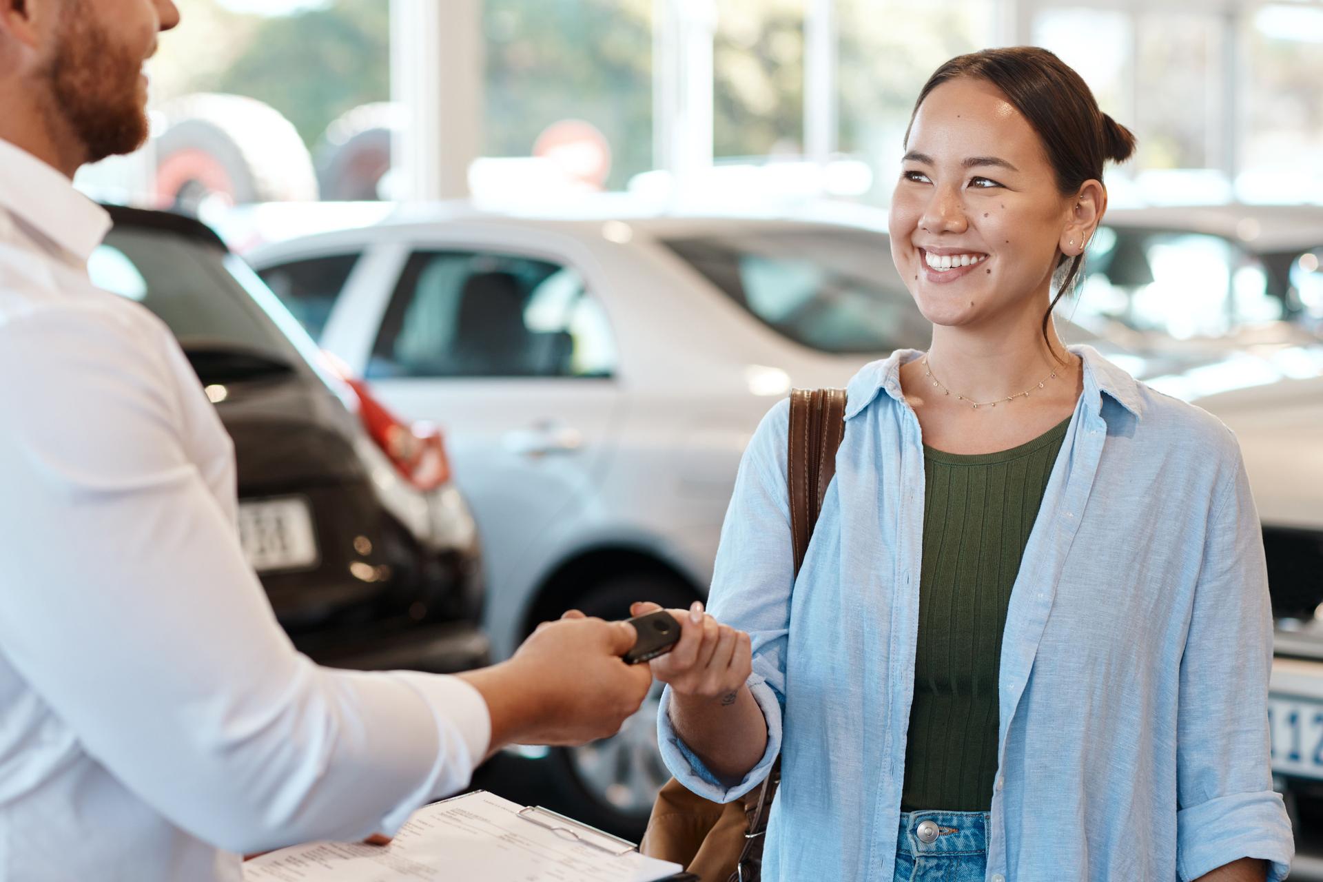 Shot of a car salesman handing over keys to a customer