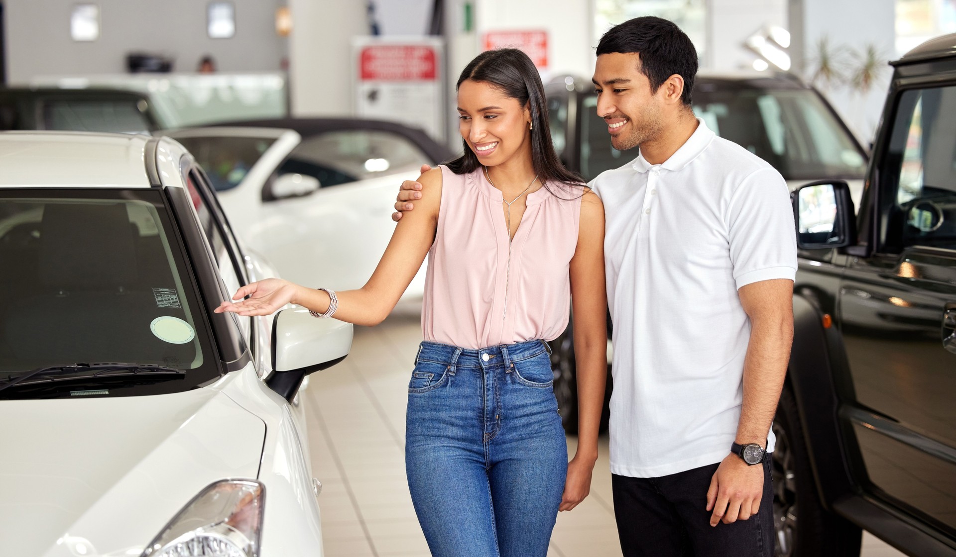 Shot of a young couple looking at cars at a car dealership